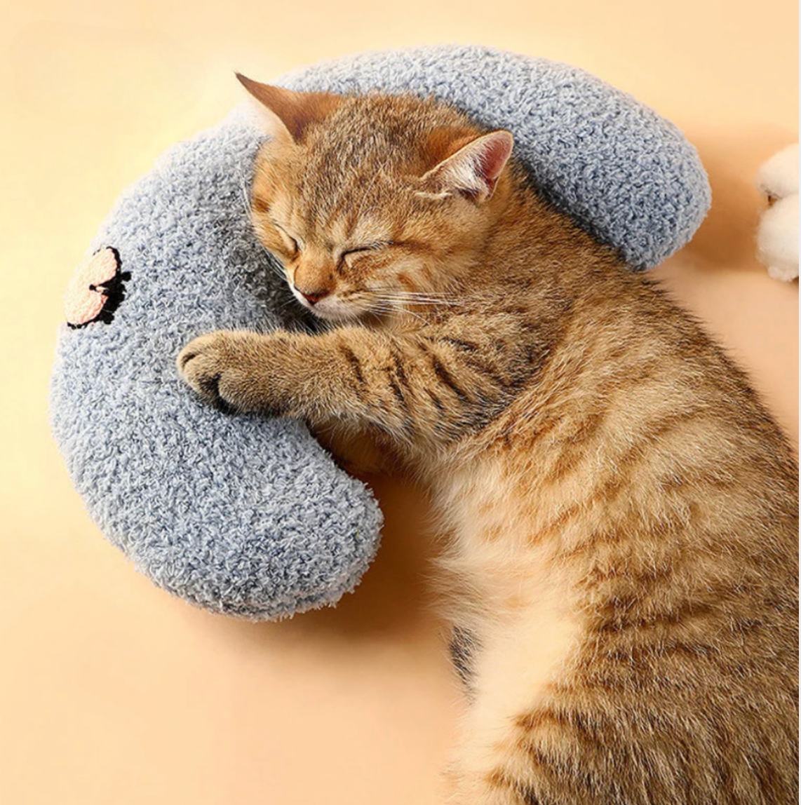 A relaxed tabby cat snuggled up to a blue HappinessPaws calming pillow