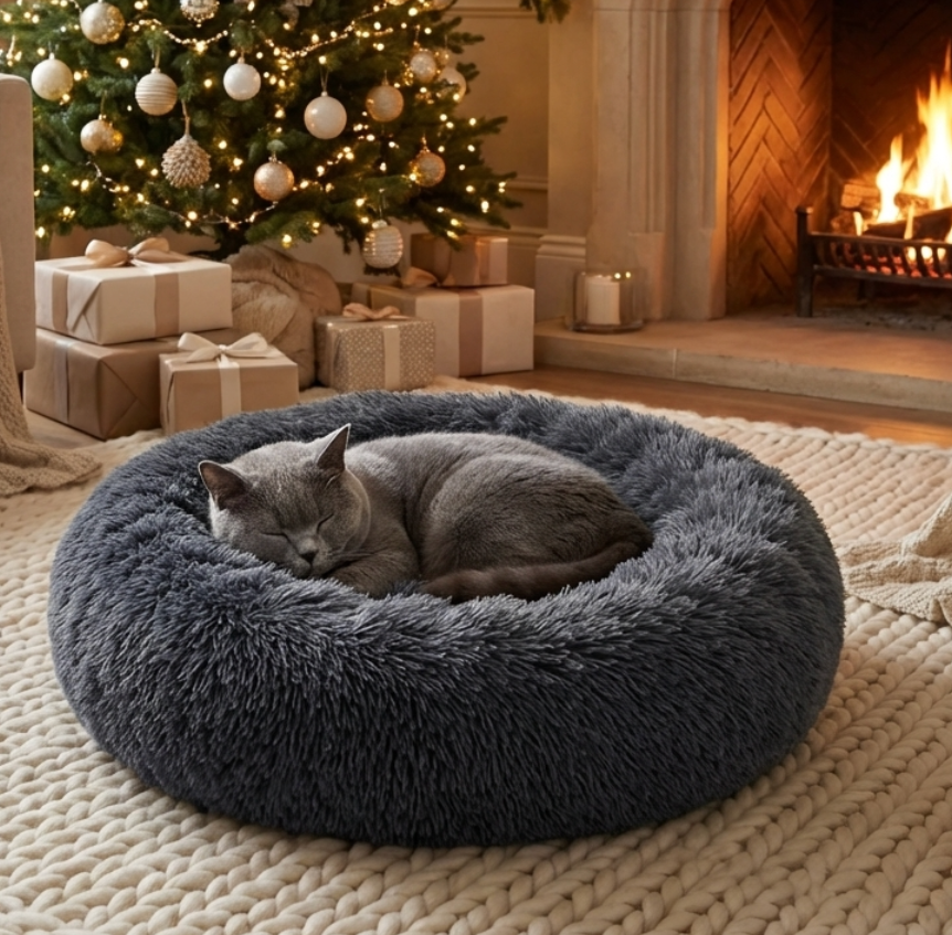 Grey cat sleeping in a fluffy grey Cozy Cocoon bed by HappinessPaws™ in front of a Christmas tree and fireplace.
