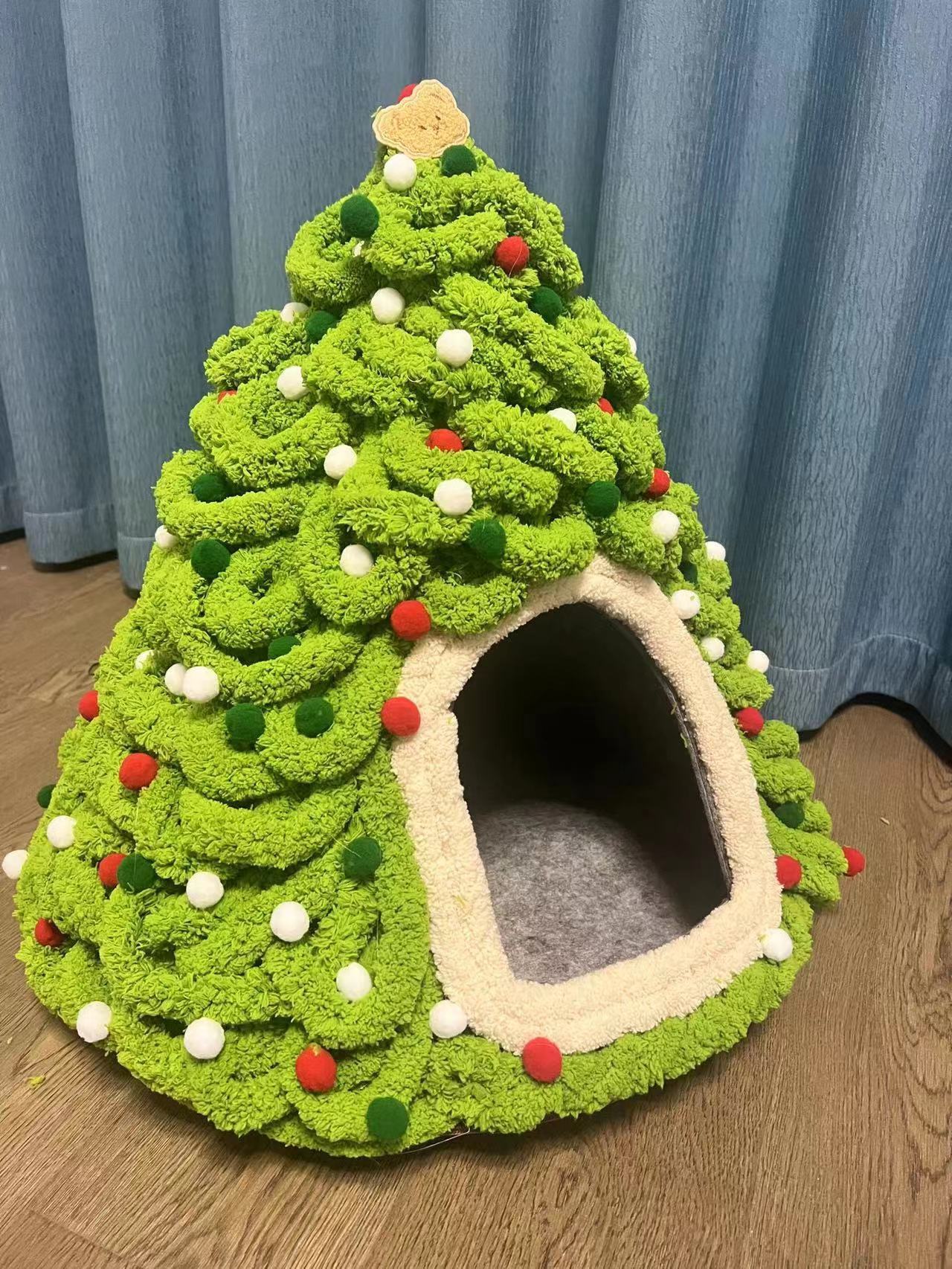 Fully decorated Christmas tree-shaped cat bed with green fabric and red accents, ready for the holiday season.