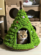 Golden cat snug inside a Christmas tree-shaped cat bed placed in a cozy indoor setting.