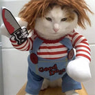 Cat in a Chucky costume with a red wig and a toy knife, showing a serious expression.