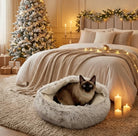 Cozy bedroom with a Siamese cat in a fluffy pet bed, Christmas tree, and decorations.