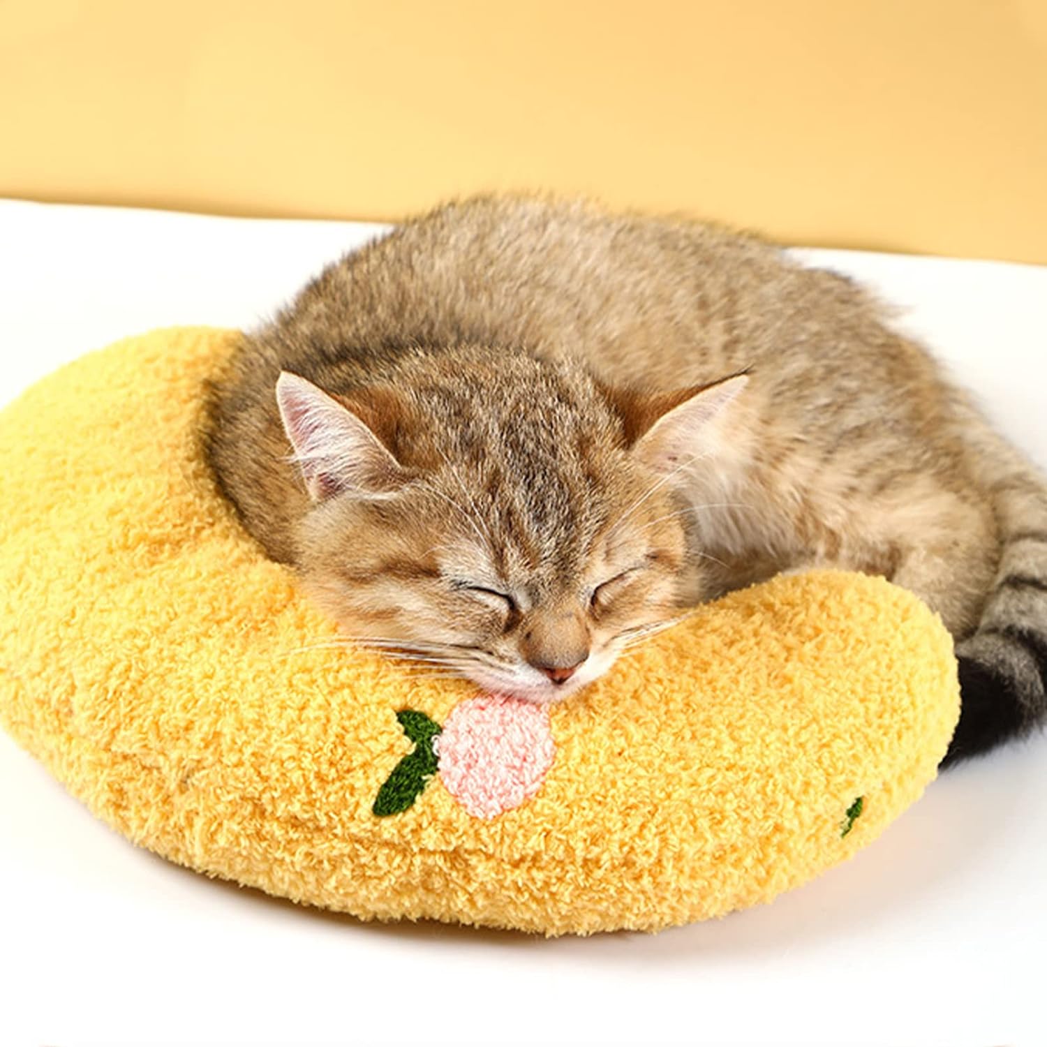 Content tabby kitten sleeping on a yellow HappinessPaws calming pillow